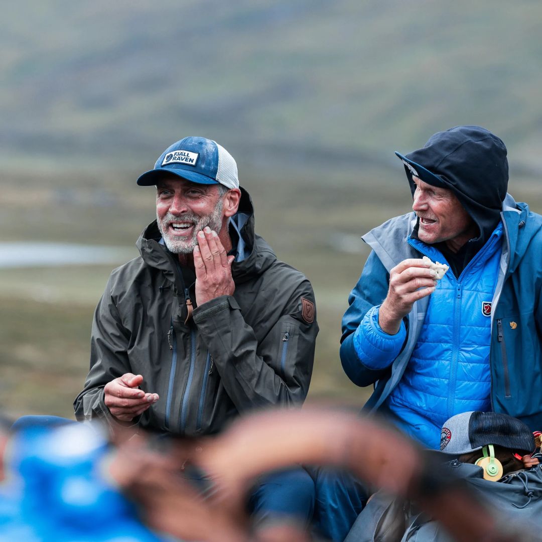 Dos hombres en actividad outdoor usando gorra Fjällräven Långtradarkeps durante descanso en la montaña.