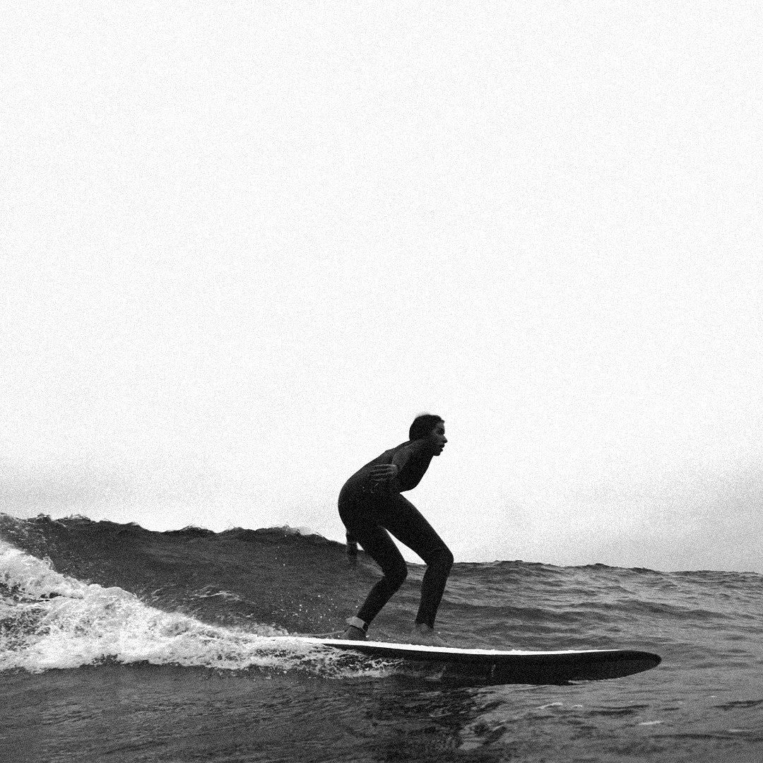 Surfista deslizándose en una ola con la tabla mini long Flysurf Cold Hawaii 8.0 en fotografía en blanco y negro.