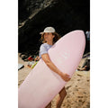 Surfista caminando por la playa con la tabla de surf rosa Flysurf Do It Your Wave 6.2 softboard con logo Flysurf en el deck.