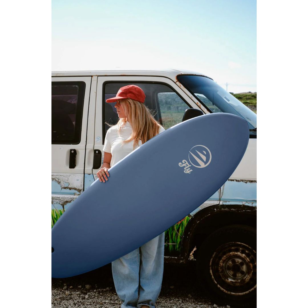 Tabla de surf FLYSURF Do It Your Wave 6.4 Blue Wave color azul apoyada frente a una furgoneta surfer, softboard evolutiva diseñada para progresar hacia una tabla corta.