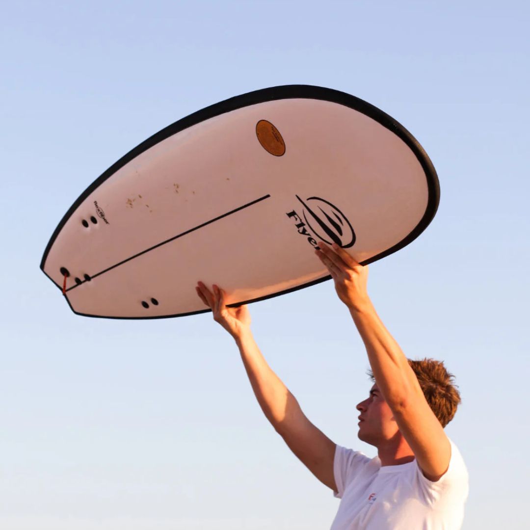 Surfista mostrando la ligereza de la tabla de surf Flysurf The Traveller 6.6 al levantarla con facilidad.