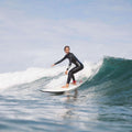 Surfista cabalgando una ola con la tabla evolutiva Flysurf The Traveller 6.6 blanca, diseñada para progresar de principiante a intermedio.