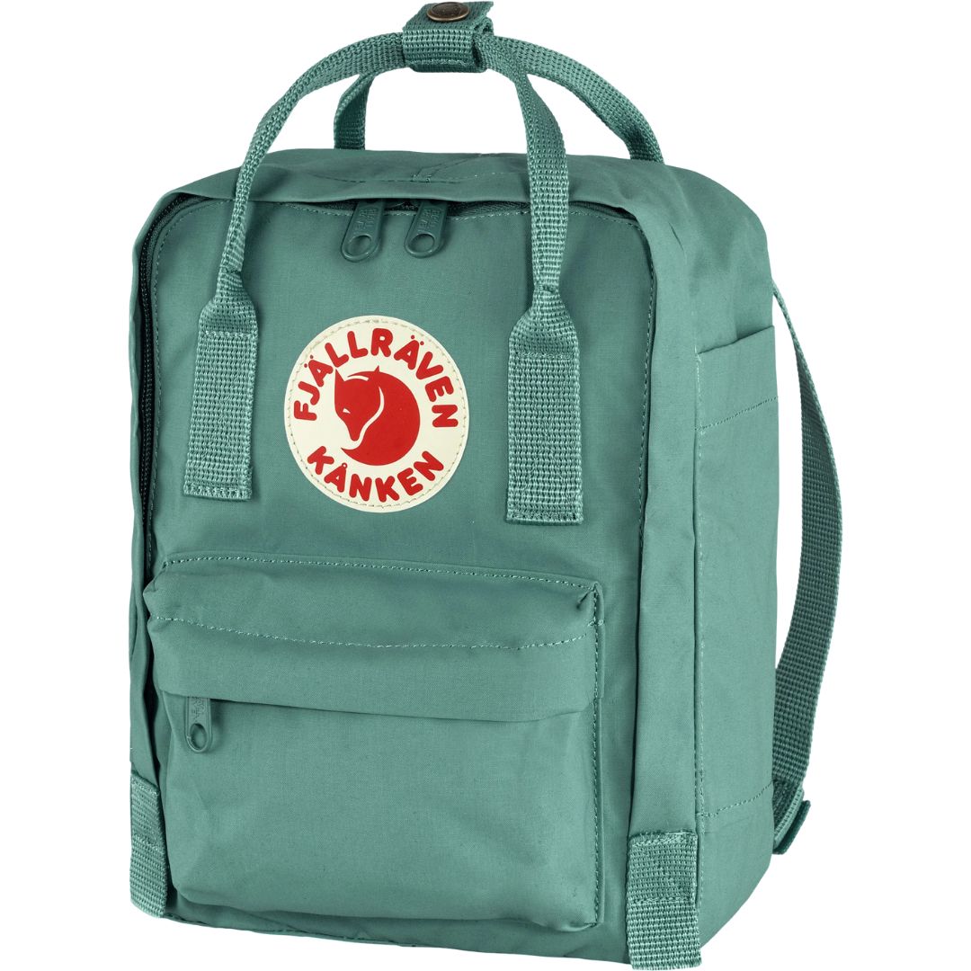 Vista frontal en ángulo de la mochila Fjällräven Kånken Mini en color Frost Green, con logo reflectante y bolsillo exterior con cremallera