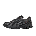 New Balance 1906R Grey Matter, vista lateral interior, upper de malla negra con overlays plateados, logo N negro y plateado y detalles en negro en suela.