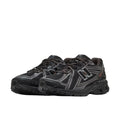 New Balance 1906R Grey Matter, vista par lateral frontal, upper de malla negra con overlays plateados, logo N negro y plateado y detalles en negro en suela.
