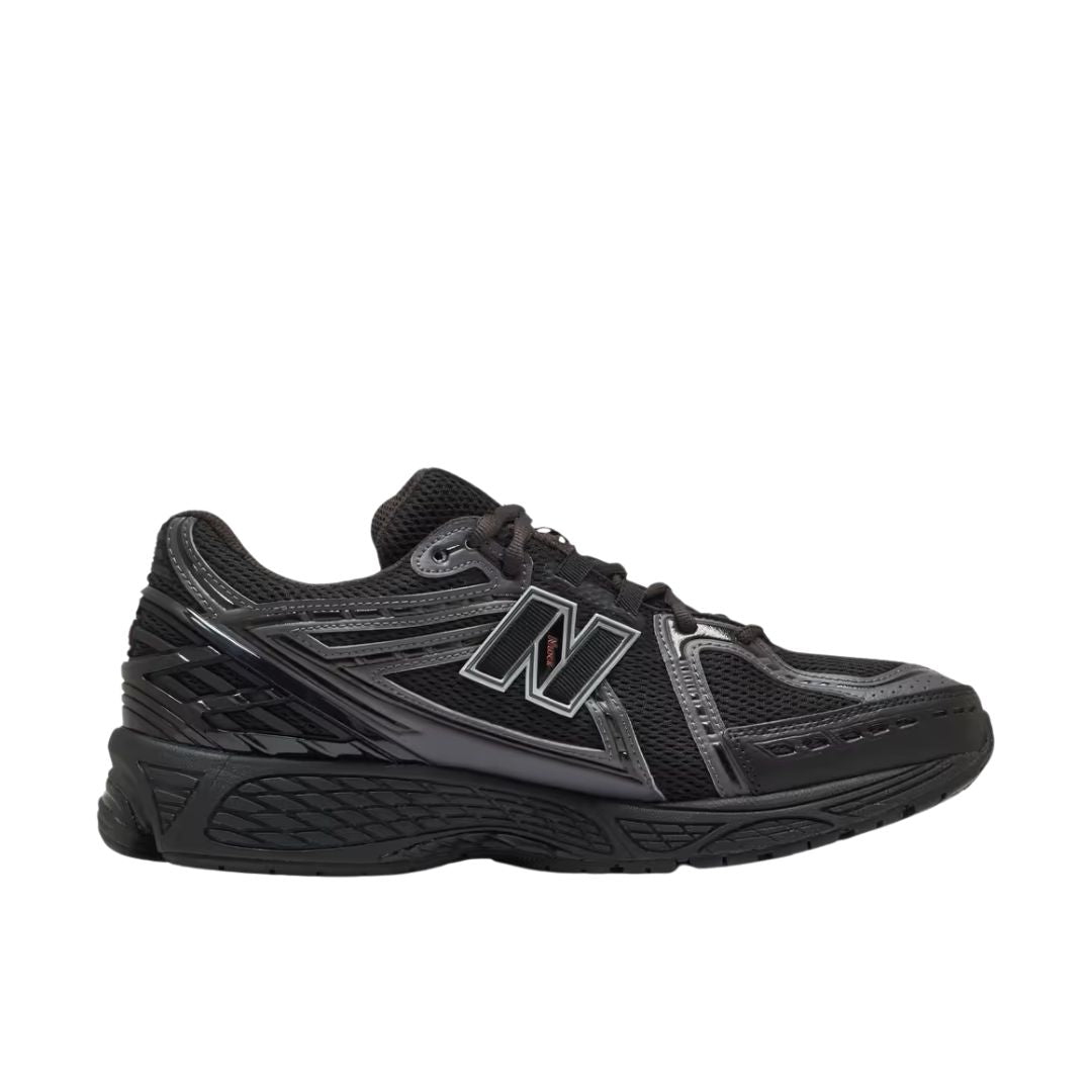 New Balance 1906R Grey Matter, vista lateral exterior, upper de malla negra con overlays plateados, logo N negro y plateado y detalles en negro en suela.