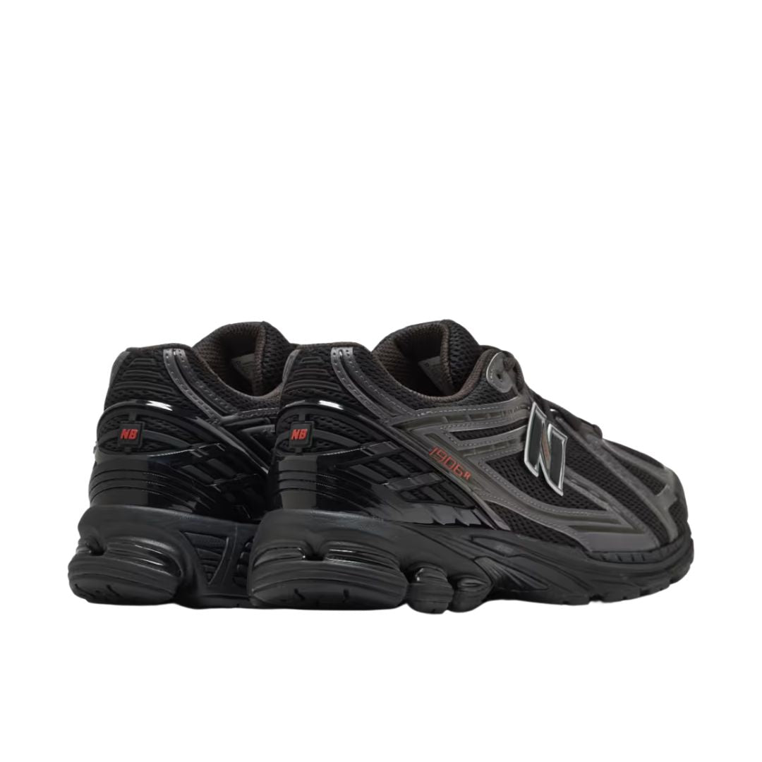 New Balance 1906R Grey Matter, vista par lateral posterior, upper de malla negra con overlays plateados, logo N negro y plateado y detalles en negro en suela.