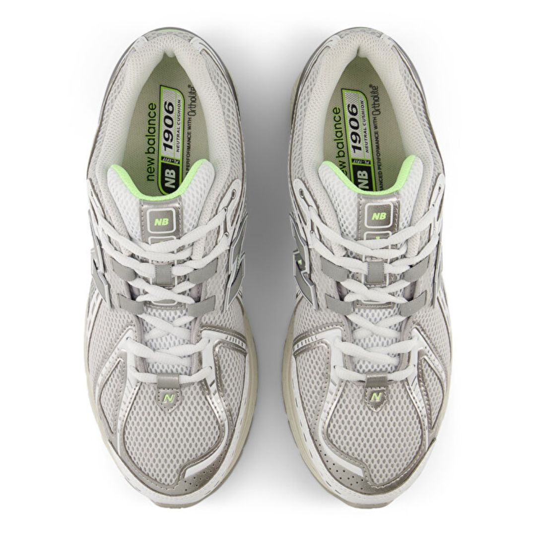 Vista cenital del par New Balance 1906R Grey Matter, upper de malla gris con cordones blancos, plantilla NB 1906 con tecnología OrthoLite y detalles verde lima.