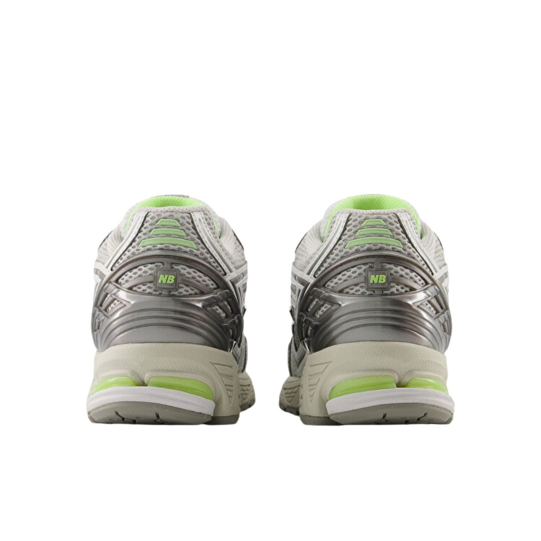 Vista trasera del par New Balance 1906R Grey Matter, contrafuerte gris con logo NB verde lima, talón con cápsula de amortiguación verde y suela crema.
