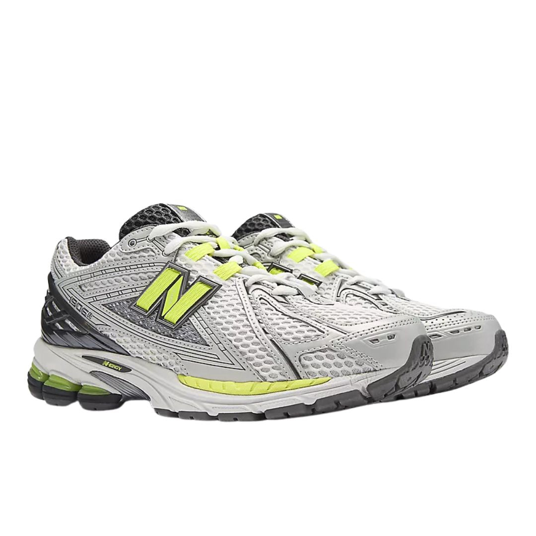 Zapatillas New Balance 1906R gris plateado y verde lima con upper de malla transpirable, logo N lateral en verde, cordones blancos y suela técnica segmentada con amortiguación.