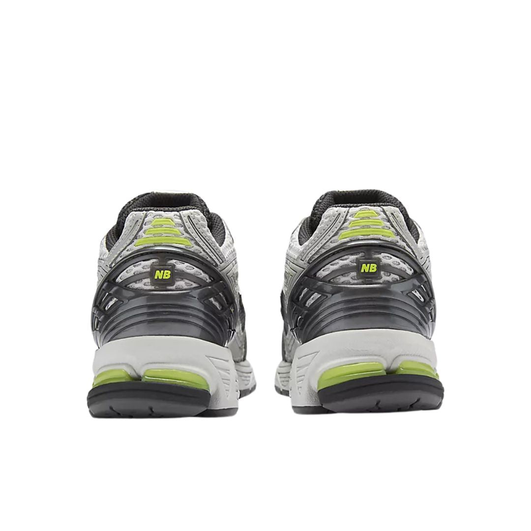 Parte trasera New Balance 1906R en gris y negro con detalles verde alkaline, refuerzo de talón, estructura rígida de soporte y suela con cápsulas de amortiguación visibles.