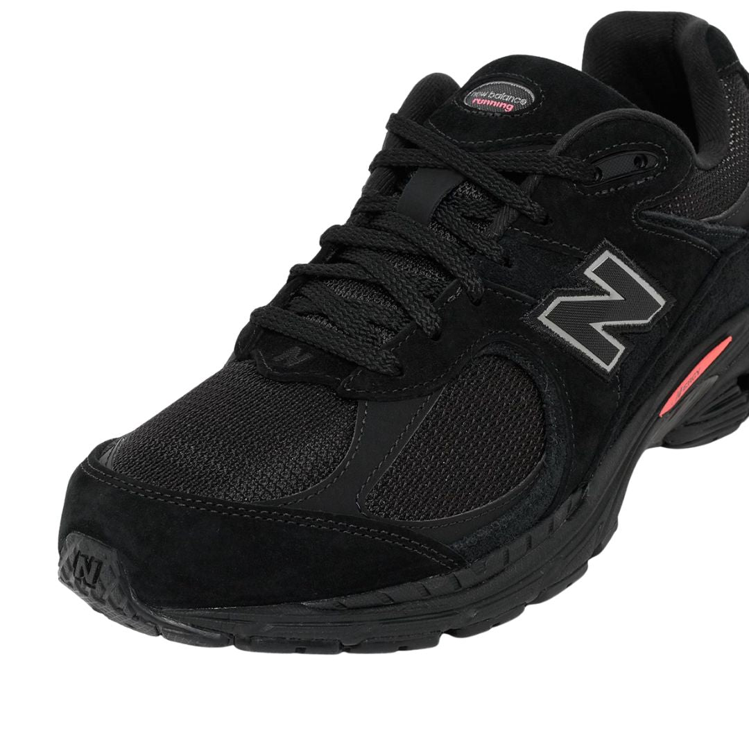 Primer plano frontal lateral de las zapatillas New Balance 2002R color negro con malla transpirable y cordones negros.