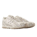 Par de New Balance 204L Timberwolf en vista tres cuartos frontal, tono beige claro, cordones, puntera de malla, logo N lateral y suela de tacos de perfil bajo.