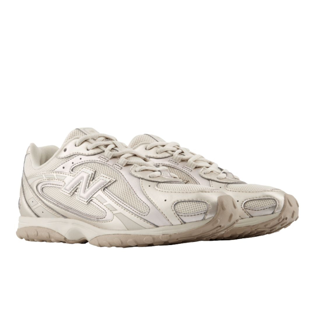 Par de New Balance 204L Timberwolf en vista tres cuartos frontal, tono beige claro, cordones, puntera de malla, logo N lateral y suela de tacos de perfil bajo.