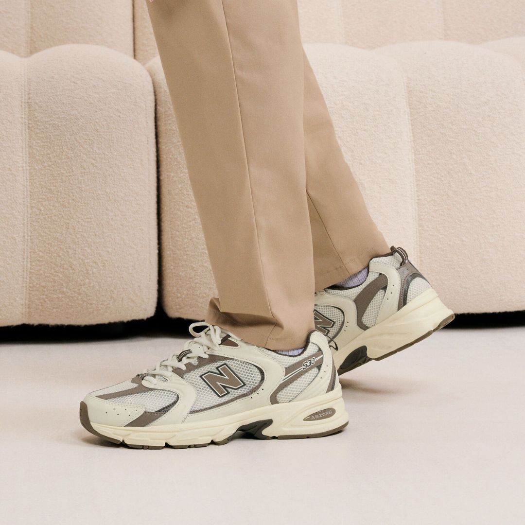 Zapatillas New Balance 530 en color turtledove, angora y mushroom vistas en uso desde perfil lateral.