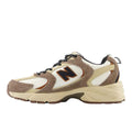 New Balance 530 Dark Mushroom/Incense/Linen: perfil lateral con superposiciones de ante marrón texturizado, malla blanca y el icónico logo N en negro y marrón.