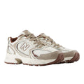 Zapatillas New Balance 530 en blanco, beige y marrón (Sea Salt/Driftwood), vista frontal en ángulo de tres cuartos mostrando ambas zapatillas, con logo N lateral y suela ABZORB visible.
