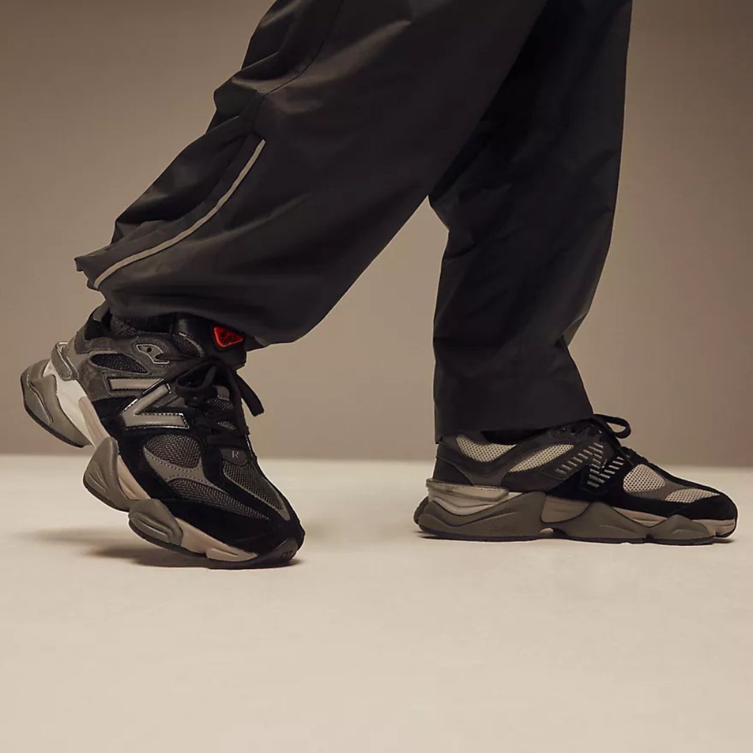 Perfil en uso de las New Balance 9060 Black Castlerock Rain Cloud mostrando entresuela sobredimensionada y estructura lateral con logo N gris.