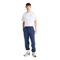 Look completo con camiseta New Balance Fish and Chips blanca, jogger azul marino y zapatillas New Balance plateadas, corte holgado y estilo urbano.