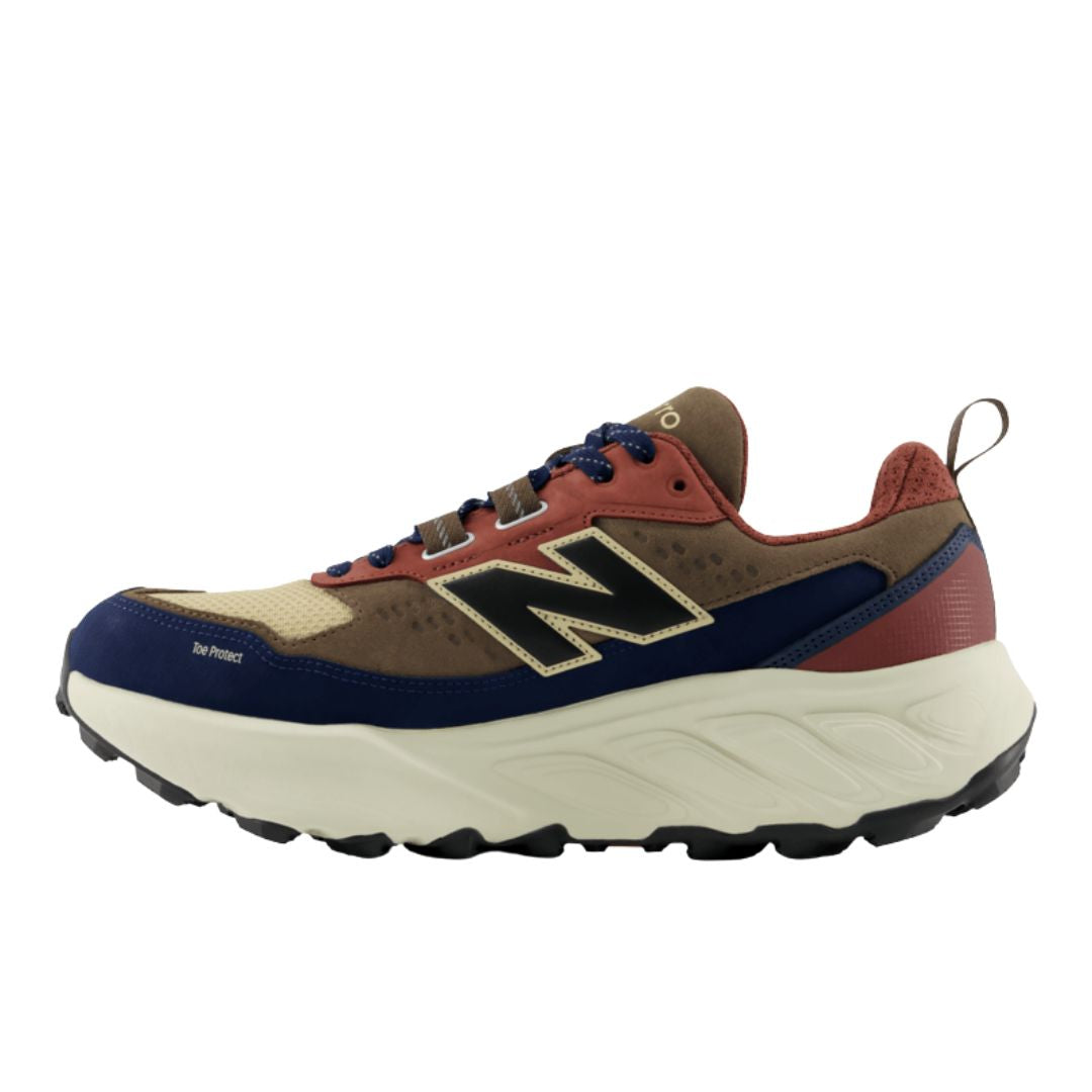 New Balance Fresh Foam X Hierro Trek Cortado Toasted Sesame vista lateral interior con refuerzo Toe Protect en puntera azul marino, upper piel marrón y malla beige, mediasuela Fresh Foam X y suela trail Vibram negra.