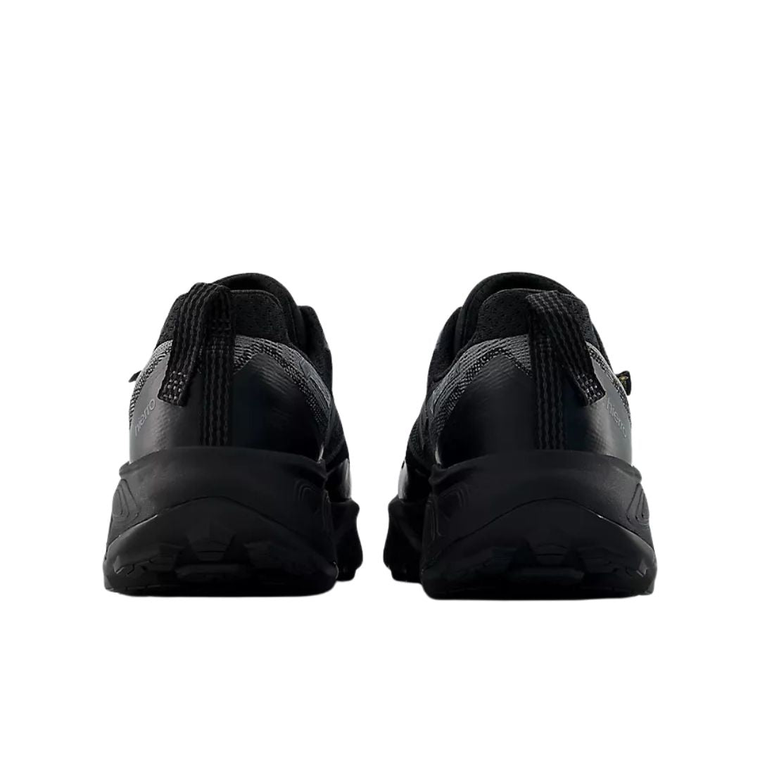 New Balance Hierro v9 GORE-TEX® en negro con Faded Black y Castlerock, vista trasera del par mostrando el contrafuerte acolchado y el lazo tirador del talón para calzarlas fácilmente.