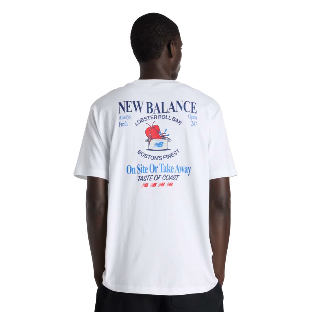 Vista trasera camiseta gráfica New Balance Lobster Roll blanca en modelo, con gran estampado Lobster Roll Bar Boston's Finest en azul marino, rojo y azul.