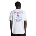 Vista trasera camiseta gráfica New Balance Lobster Roll blanca en modelo, con gran estampado Lobster Roll Bar Boston's Finest en azul marino, rojo y azul.