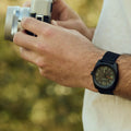 Reloj Nixon Clutch 42 All Black en la muñeca de un hombre fotografiando en exteriores con luz natural.