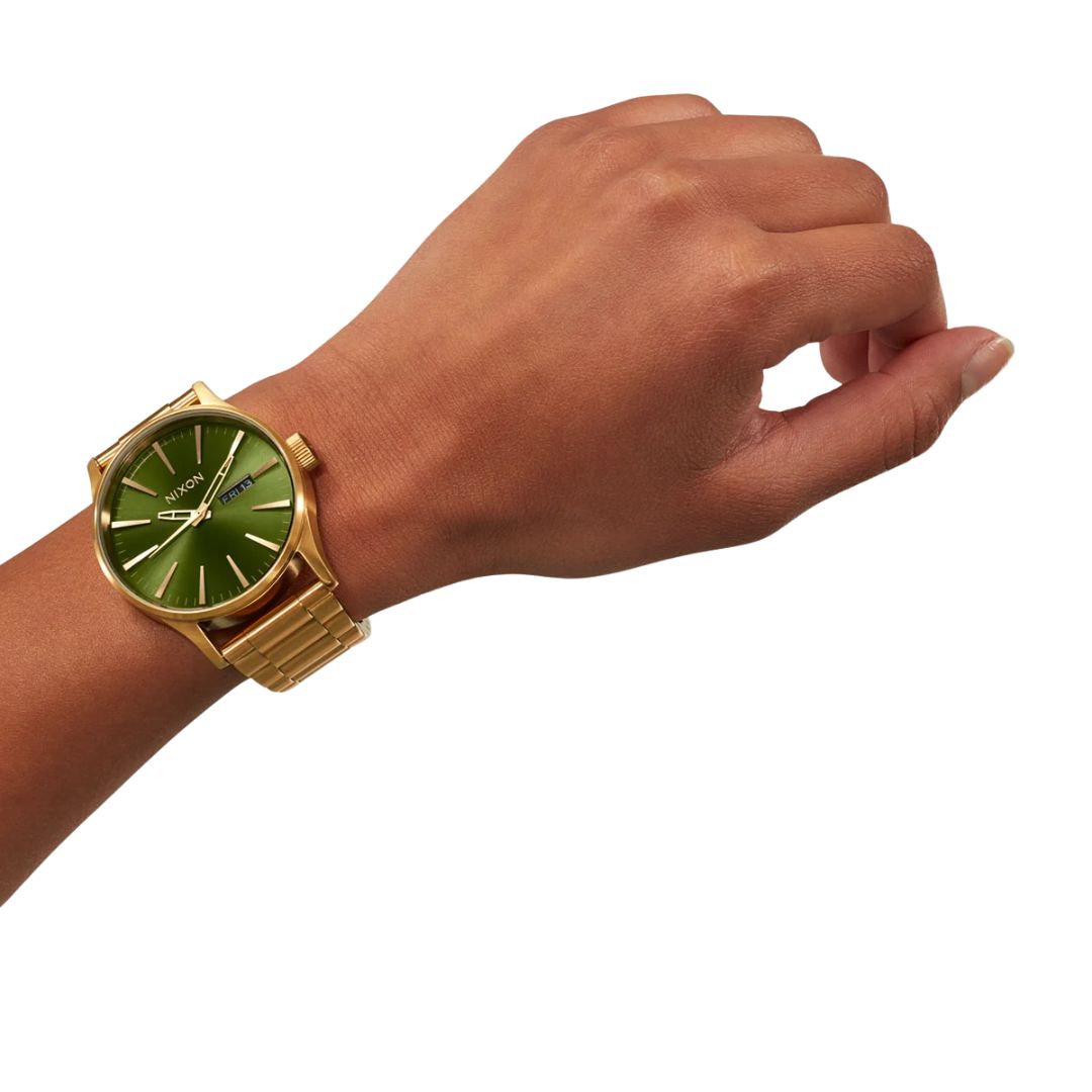 Reloj Nixon Sentry Stainless Steel dorado con esfera verde sunray en la muñeca de un modelo, vista alternativa.