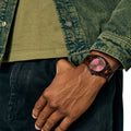 Reloj Nixon Time Teller Acetate tortoise oxblood en muñeca masculina con chaqueta vaquera verde.