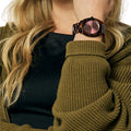 Detalle del reloj Nixon Time Teller Acetate tortoise oxblood con esfera color burdeos en muñeca femenina.