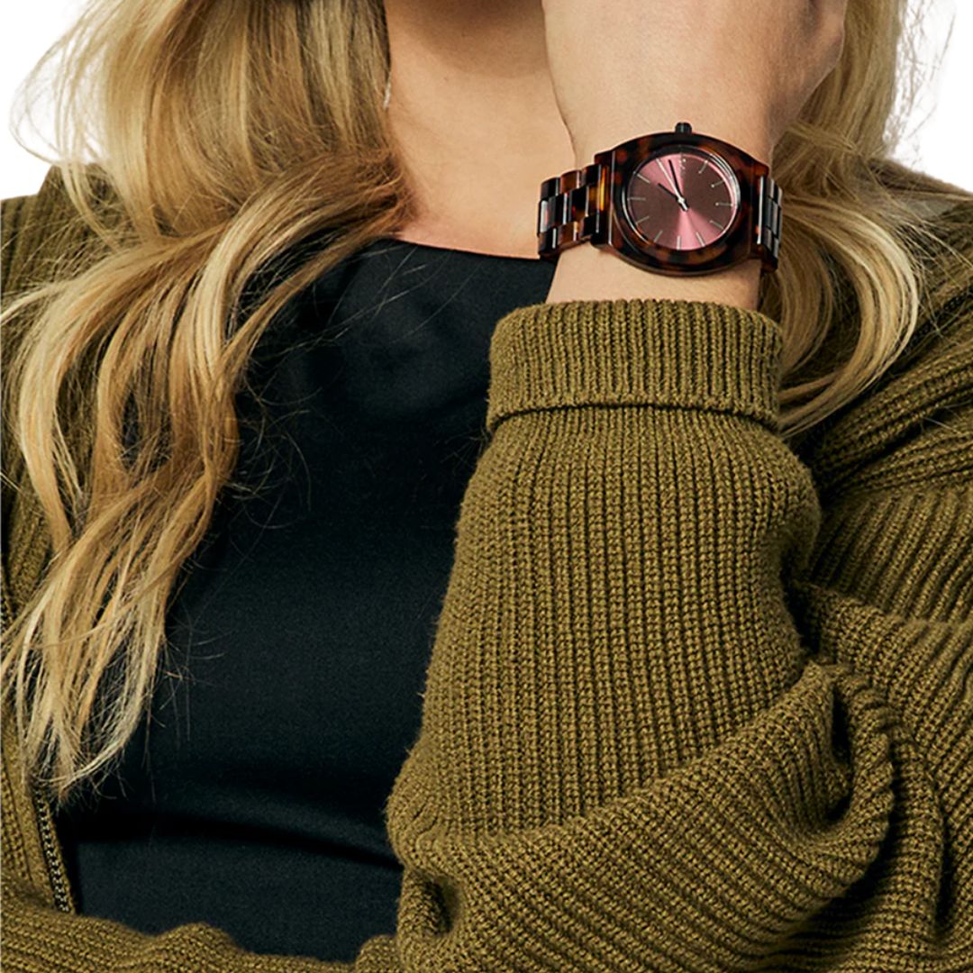 Detalle del reloj Nixon Time Teller Acetate tortoise oxblood con esfera color burdeos en muñeca femenina.