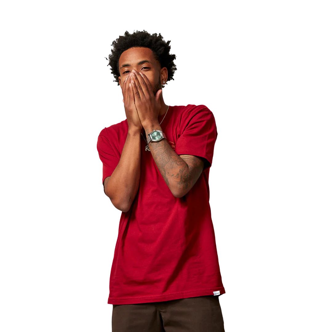 Modelo masculino luciendo el Nixon Time Teller Solar plateado con esfera verde jade y tapándose la boca.