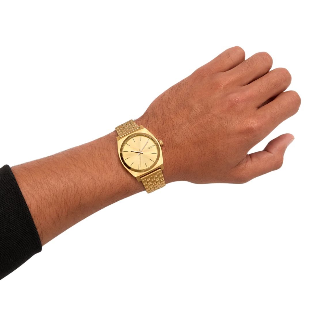 Reloj Nixon Time Teller All Gold colocado en muñeca masculina, mostrando su tamaño y diseño dorado integral.