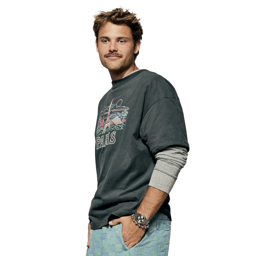 Reloj Nixon Time Teller Fisheye plateado en la muñeca de un hombre con camiseta gris.