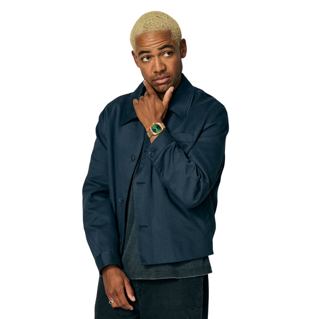 Modelo femenino luciendo el reloj Nixon Time Teller Gold Green Sunray con esfera verde y acabado dorado.