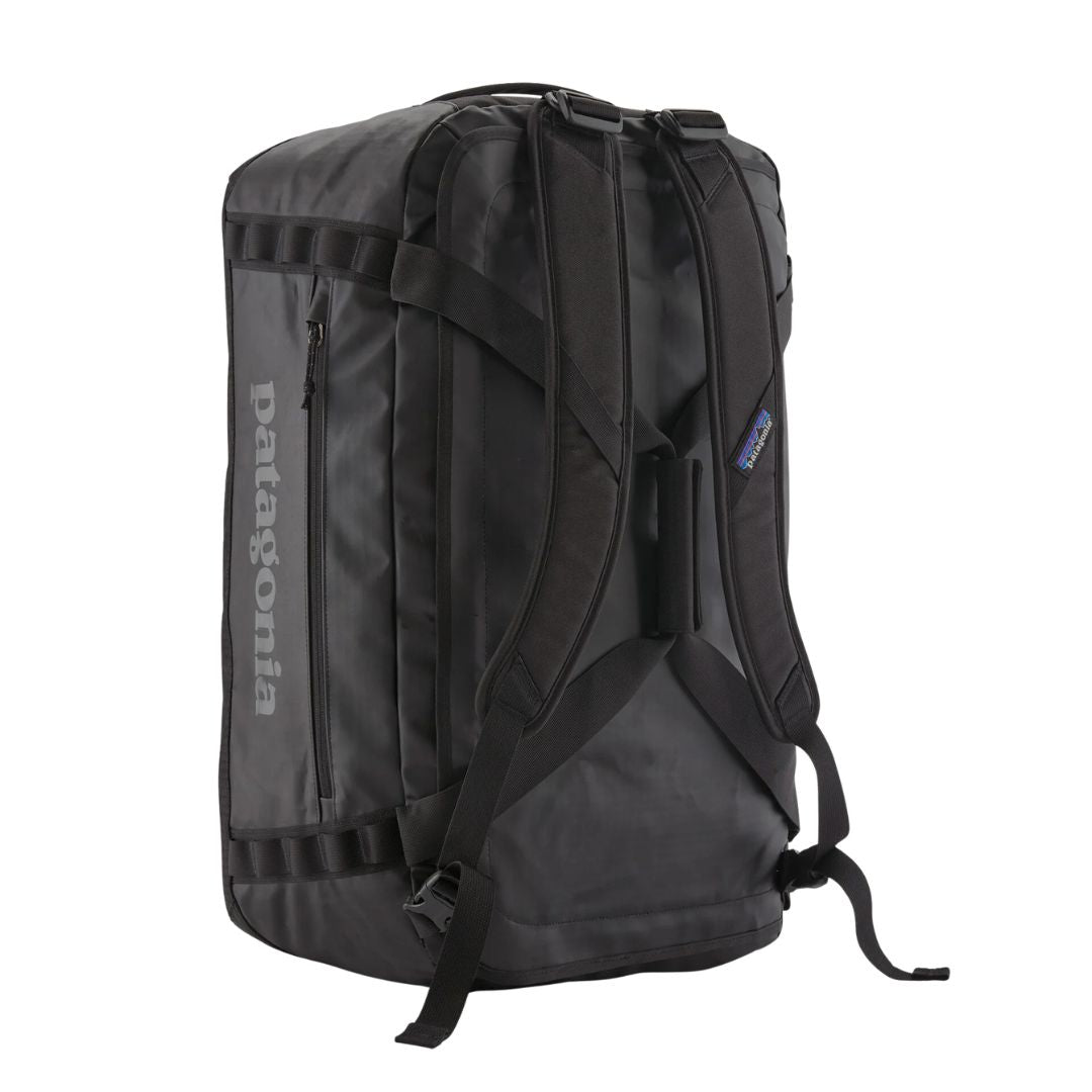 Patagonia Black Hole Duffel 40L en color black on black, vista trasera de producto sin modelo en posición vertical, mostrando las correas de hombro acolchadas y extraíbles desplegadas para uso como mochila, la base acolchada, los puntos de sujeción laterales y la etiqueta Patagonia azul.