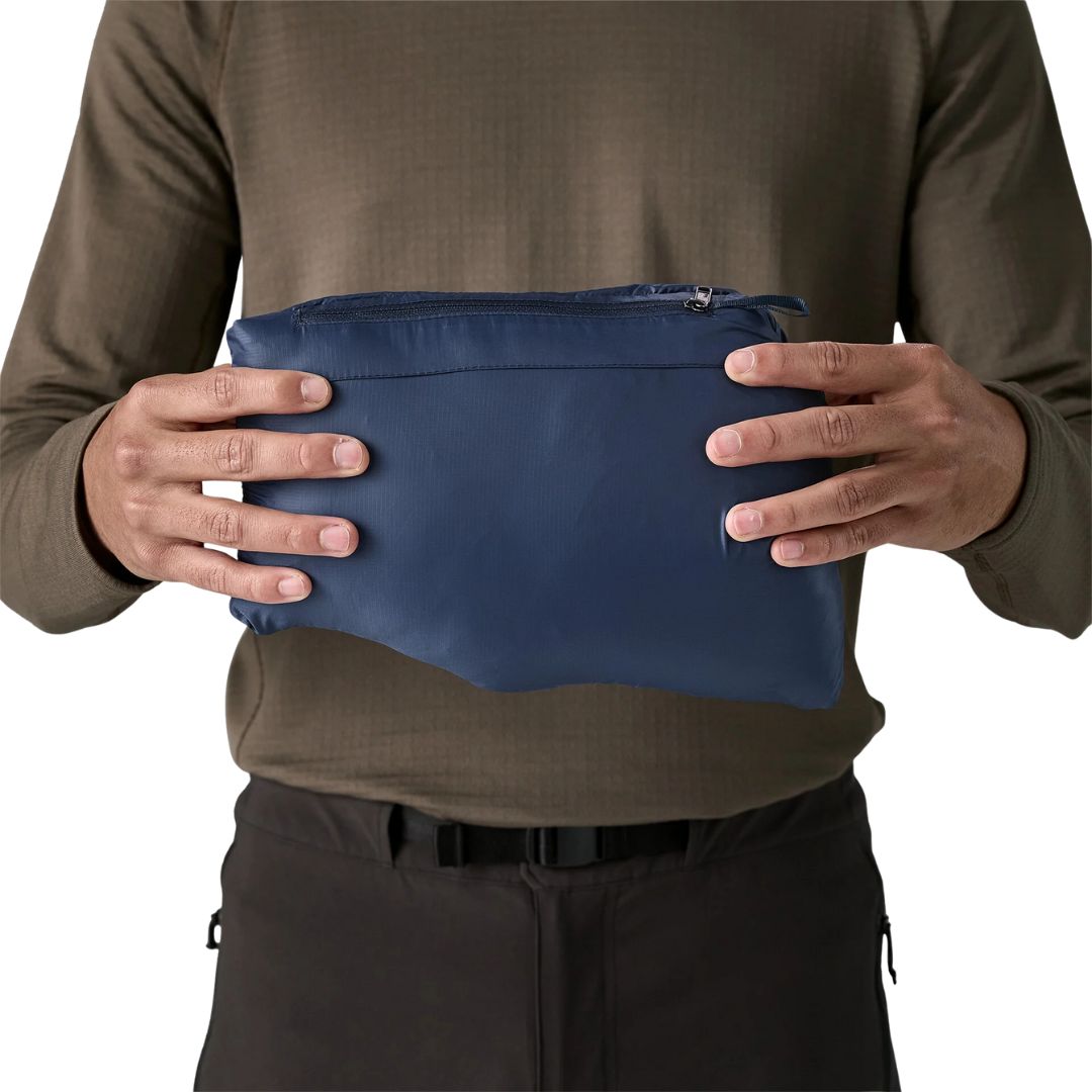 Chaqueta Patagonia Down Sweater New Navy para hombre, comprimida dentro de su propio bolsillo tipo pouch compacto.