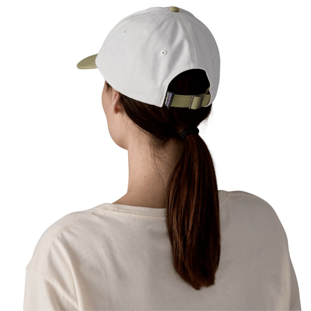 Patagonia Fitz Roy Icon Trad Cap en color blanco Birch White con visera verde Gumtree Green — vista lateral con logo Patagonia bordado en la copa, llevada por una mujer.