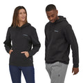 Modelos masculino y femenino vistiendo la Patagonia Fitz Roy Icon Uprisal Hoody en color negro, resaltando la versatilidad y diseño unisex.