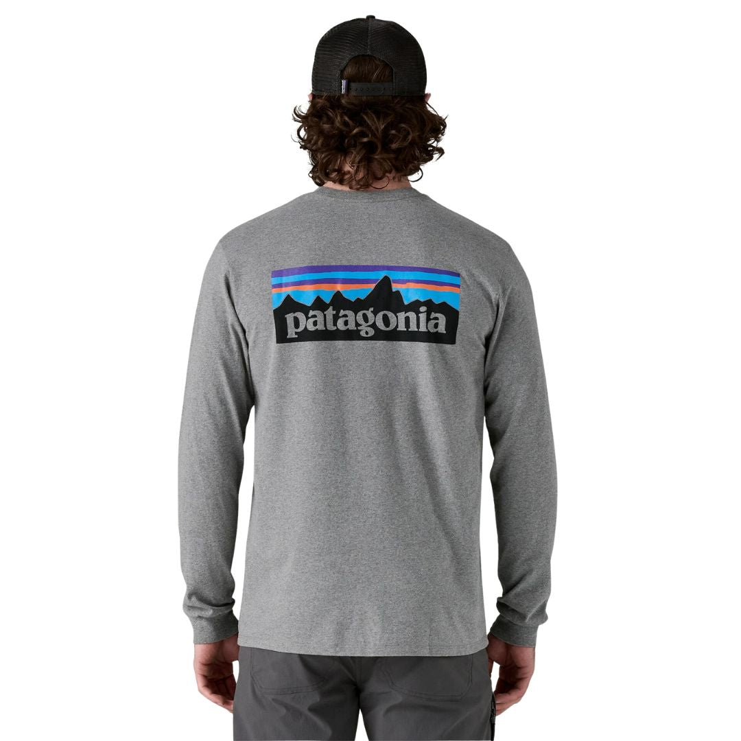 Vista trasera de hombre con camiseta Patagonia L/S P‑6 Logo Responsibili‑Tee en color Gravel Heather, con diseño gráfico del logo a gran escala.