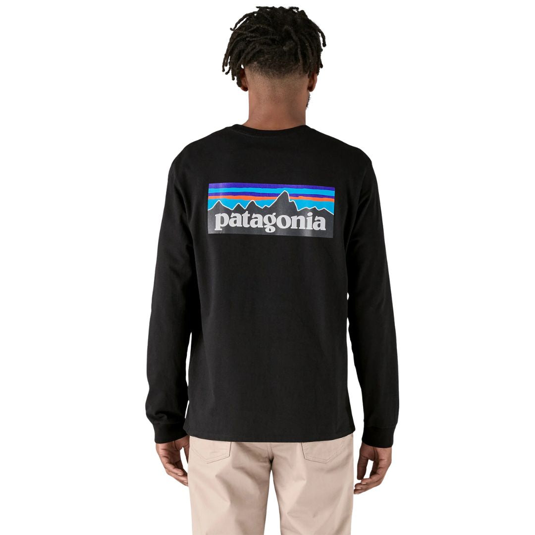Vista trasera de hombre con la camiseta Patagonia L/S P‑6 Logo Responsibili‑Tee negra, con logo gráfico clásico de montañas.