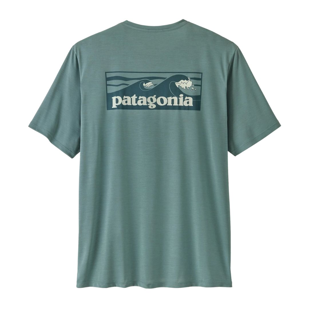 Patagonia Men's Capilene Cool Daily Shirt Boardshort Logo en color blue sage, vista trasera de producto plano sin modelo, mostrando el estampado completo Boardshort Logo con olas de surf en tonos verde petróleo y crema enmarcadas en rectángulo sobre fondo verde azulado jaspeado.