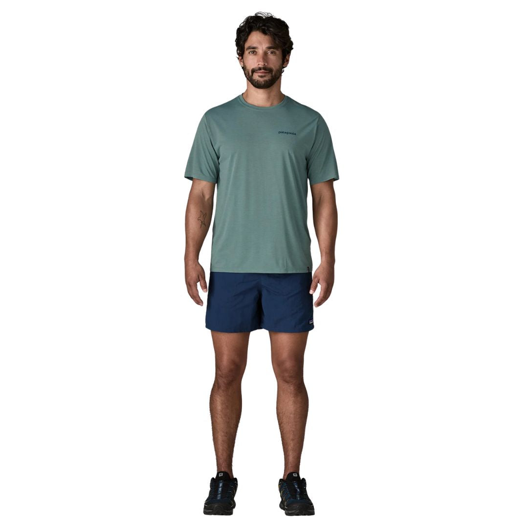 Patagonia Men's Capilene Cool Daily Shirt Boardshort Logo en color blue sage, vista frontal completa con modelo combinada con bañador azul marino y zapatillas de trail, mostrando el corte regular fit y la ligereza del tejido técnico Capilene.