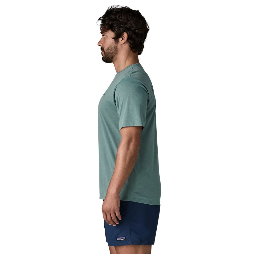 Patagonia Men's Capilene Cool Daily Shirt Boardshort Logo en color blue sage, vista lateral con modelo, mostrando el corte regular fit, las mangas montadas y el tejido jaspeado de poliéster reciclado en verde azulado.