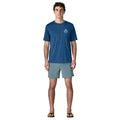 Patagonia Men's Capilene Cool Daily Shirt Great Waves en color clement blue light clement blue x-dye, vista frontal completa con modelo combinada con bañador y chanclas, mostrando el corte regular fit y la ligereza del tejido técnico Capilene.