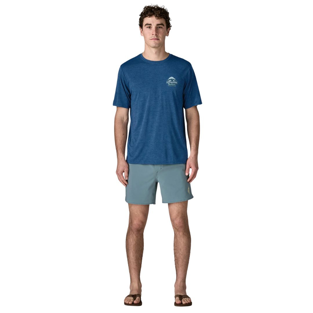 Patagonia Men's Capilene Cool Daily Shirt Great Waves en color clement blue light clement blue x-dye, vista frontal completa con modelo combinada con bañador y chanclas, mostrando el corte regular fit y la ligereza del tejido técnico Capilene.