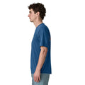 Patagonia Men's Capilene Cool Daily Shirt Great Waves en color clement blue light clement blue x-dye, vista lateral con modelo, mostrando el corte regular fit, las mangas montadas y el estampado Great Pacific Iron Works visible en la espalda.