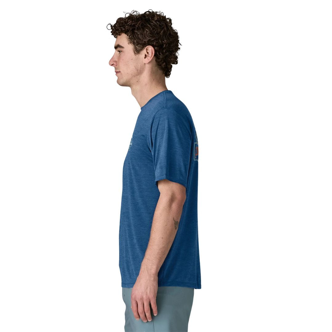 Patagonia Men's Capilene Cool Daily Shirt Great Waves en color clement blue light clement blue x-dye, vista lateral con modelo, mostrando el corte regular fit, las mangas montadas y el estampado Great Pacific Iron Works visible en la espalda.