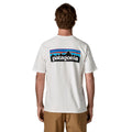 Camiseta Patagonia P-6 Logo Responsibili-Tee en color blanco (Fiber White), modelo visto de espaldas mostrando el icónico logotipo P-6 con las montañas y el degradado de colores.